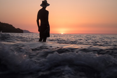 站在浅滩上面对夕阳的人的剪影